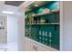 Elegant bar area with wooden shelves, green backdrop, mirrored cabinets, and stylish glassware at 6611 N 79Th Pl, Scottsdale, AZ 85250