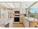 Bright kitchen with white cabinets, tile countertops, modern appliances, and a large window at 6717 E Aire Libre Ln, Scottsdale, AZ 85254