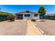 A spacious backyard with rock landscaping, small bushes, a covered area, and a gray house at 7343 E Juanita Ave, Mesa, AZ 85209
