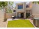 A green backyard with artificial turf, brick patio, sliding glass doors and a view of the home's exterior at 7716 S Rita Ln, Tempe, AZ 85284
