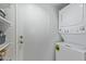 A compact laundry area featuring a stacked washer and dryer with a white door and shelving at 7716 S Rita Ln, Tempe, AZ 85284