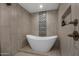Modern soaking tub with tiled walls and bronze fixtures in a renovated bathroom at 8343 E Quarterhorse Trl, Scottsdale, AZ 85258
