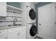 Laundry area with stackable washer and dryer, sink, white cabinets and modern backsplash at 8343 E Quarterhorse Trl, Scottsdale, AZ 85258