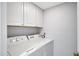A well-maintained laundry room with white appliances and overhead cabinets for storage at 848 E Morningside Dr, Phoenix, AZ 85022