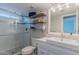 Well-lit bathroom featuring glass shower, vanity with sink, and shelving over the toilet at 12042 S 44Th St, Phoenix, AZ 85044