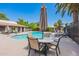 Relaxing community pool with lounge chairs, tables, and a sun umbrella surrounded by lush landscaping at 1402 E Guadalupe Rd # 207, Tempe, AZ 85283