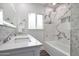 Bright bathroom featuring double sinks, modern fixtures, and decorative tile in the shower and backsplash at 1613 W Flower N Cir, Phoenix, AZ 85015