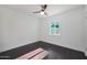 A simple bedroom featuring a window and ceiling fan over dark wood floors at 1613 W Flower N Cir, Phoenix, AZ 85015