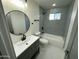 Updated bathroom featuring a modern vanity, round mirror, and tiled shower over tub at 1930 W Missouri Ave, Phoenix, AZ 85015