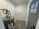 Laundry room with modern hot water tank, wood-look flooring, and access door at 1930 W Missouri Ave, Phoenix, AZ 85015