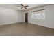 Simple living room showcasing neutral tile flooring, a ceiling fan, a window, and a dark wood door at 2432 W Echo Ln, Phoenix, AZ 85021