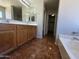 Bright bathroom featuring a double sink vanity, tiled floor, large mirror, and en suite entrance at 25748 W Siesta Way, Buckeye, AZ 85326