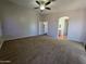 A neutral bedroom with a ceiling fan, carpeted floor, and view to the hallway and en suite bathroom at 25748 W Siesta Way, Buckeye, AZ 85326