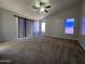 A large bedroom with a ceiling fan, plush carpet, multiple windows, and vertical blinds at 25748 W Siesta Way, Buckeye, AZ 85326