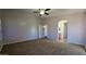 A neutral bedroom with a ceiling fan, carpeted floor, and view to the hallway and en suite bathroom at 25748 W Siesta Way, Buckeye, AZ 85326