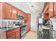 Galley kitchen featuring dark countertops, stainless steel appliances, and warm wood cabinets at 2625 E Indian School Rd # 206, Phoenix, AZ 85016