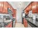 Galley kitchen featuring dark countertops, stainless steel appliances, and warm wood cabinets at 2625 E Indian School Rd # 206, Phoenix, AZ 85016