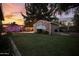 Expansive backyard featuring a covered patio, green grass, and an art-adorned shed at 3018 E Mulberry Dr, Phoenix, AZ 85016