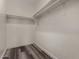 Bright walk-in closet with white walls, wood-look floors, and built-in shelving for optimal storage space at 30938 W Mitchell Dr, Buckeye, AZ 85396