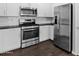 Well-equipped kitchen with stainless steel appliances, white cabinetry, black countertops, and wood-look tile flooring at 3131 S Mingus Dr, Chandler, AZ 85286