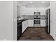 Bright kitchen featuring white cabinets, stainless steel appliances, black countertops, and dark wood-look flooring at 3131 S Mingus Dr, Chandler, AZ 85286
