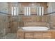 Stunning bathroom featuring a tiled shower and tub, with natural stone accents and bright natural light at 3215 E Constance Way, Phoenix, AZ 85042