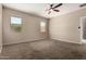 A large open bedroom with ample light from the two windows and plush carpet flooring at 42098 W Balsa Dr, Maricopa, AZ 85138