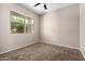 Bright, carpeted bedroom features ceiling fan and large window with views at 42098 W Balsa Dr, Maricopa, AZ 85138