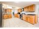 Well-lit kitchen with wood cabinets, tiled floor, stainless steel appliances, and breakfast bar at 4414 S Ventura Dr, Tempe, AZ 85282