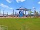 Community park with playground, sunshades, slides, climbing areas, and green grass at 5464 S 246Th Ln, Buckeye, AZ 85326