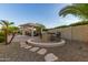 Lush backyard oasis with pergola-covered seating area, bar, grill, and stepping stones amidst desert landscaping at 6648 S Lyon Dr, Gilbert, AZ 85298