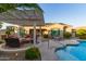 Backyard with a pergola and seating, adjacent to the pool and spa, lounge chairs and well kept landscaping at 6648 S Lyon Dr, Gilbert, AZ 85298