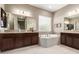 Luxurious bathroom with dual vanities, soaking tub, tile floors, and ample natural light at 6648 S Lyon Dr, Gilbert, AZ 85298