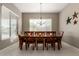 Elegant dining room featuring a wooden table, six chairs, modern light fixture, and a large window with natural light at 6648 S Lyon Dr, Gilbert, AZ 85298
