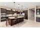 Modern kitchen featuring an island with seating, stainless steel appliances, pendant lighting, and dark wood cabinetry at 6648 S Lyon Dr, Gilbert, AZ 85298