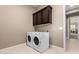 Functional laundry room with included washer, dryer, and upper dark wood cabinets at 6648 S Lyon Dr, Gilbert, AZ 85298