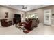 Comfortable living room with neutral paint, tiled floor, a ceiling fan, and plush leather seating surrounding an entertainment center at 6648 S Lyon Dr, Gilbert, AZ 85298
