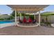 A cozy backyard with a pergola-covered seating area, fire pit, and adjacent to the pool and spa at 6648 S Lyon Dr, Gilbert, AZ 85298