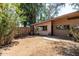 View of the backyard featuring a block home with a concrete slab patio and wood fence surrounded by mature trees at 725 S Power Rd # 101, Mesa, AZ 85206
