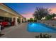 Backyard patio and pool illuminated at dusk. Lush green landscaping around privacy wall at 10152 E Aster Dr, Scottsdale, AZ 85260