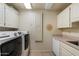 Bright laundry room with front loading washer and dryer and white cabinets at 10152 E Aster Dr, Scottsdale, AZ 85260