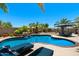 Inviting backyard pool featuring a rock waterfall, lounge chairs, and lush tropical landscaping at 1078 W Desert Aster Rd, San Tan Valley, AZ 85143