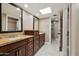 Bathroom featuring dual sinks with granite counters, wooden cabinets, and a doorway to the shower at 14029 N Burning Tree Pl, Phoenix, AZ 85022
