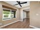 An empty room with wood-look flooring, a ceiling fan, and a large window showing the backyard at 14029 N Burning Tree Pl, Phoenix, AZ 85022