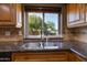 Up-close view of a kitchen sink and granite countertop with a window showcasing a tree at 14029 N Burning Tree Pl, Phoenix, AZ 85022
