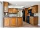 A stylish kitchen with wood cabinets, a tile backsplash, granite countertops, and black appliances at 14029 N Burning Tree Pl, Phoenix, AZ 85022
