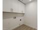 Bright laundry room with wood-look flooring and white cabinets for ample storage at 1444 E Boston St, Chandler, AZ 85225