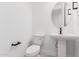 Stylish powder room featuring a pedestal sink, round mirror and modern fixtures at 16981 W Cameron Dr, Surprise, AZ 85388