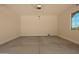 Spacious two-car garage with a smooth concrete floor and natural lighting from the side window at 17304 W Royal Palm Rd, Waddell, AZ 85355