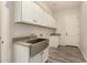 Well-lit laundry room features stainless steel sink, ample cabinet space, and stylish wood-look flooring at 17304 W Royal Palm Rd, Waddell, AZ 85355